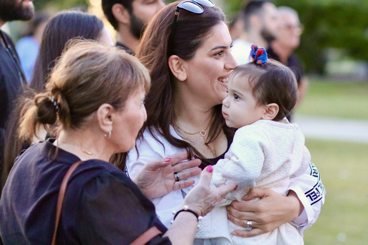 A photo representing three generations, as a grandmother reaches for her granddaughter. 