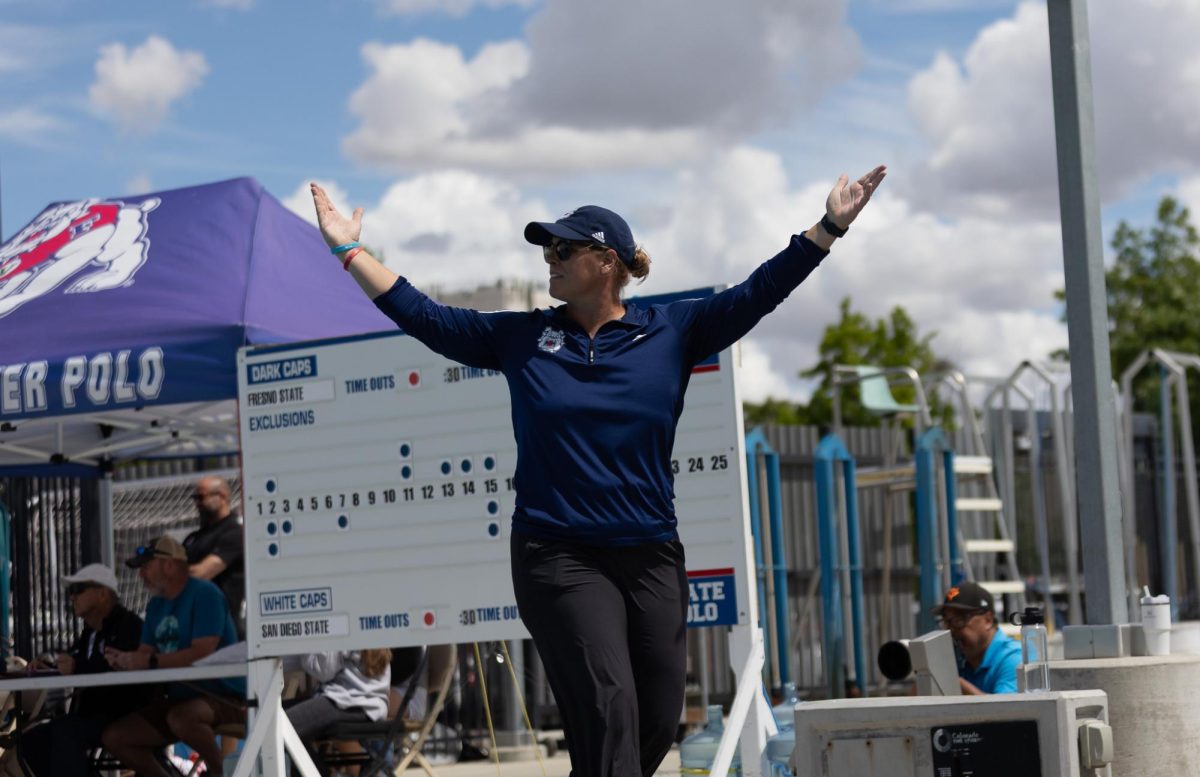 Fresno State water polo Head Coach Natalie Benson raises her arms during the Bulldogs' semifinal match against the San Diego State Aztecs on April 11 at the Fresno State Aquatics Center. A 16-15 victory propelled the Bulldogs into the GCC Title game for the sixth consecutive season.