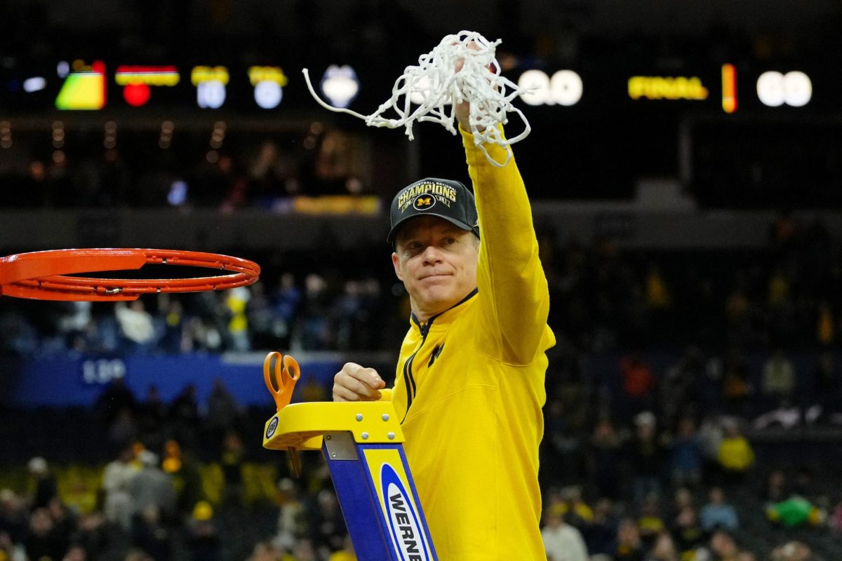 Apr 6, 2026; Indianapolis, IN, USA; Michigan Wolverines head coach Dusty May waves to fans after cutting the net after their win against the UConn Huskies in the national championship of the Final Four of the men's 2026 NCAA Tournament between the  and the Michigan Wolverines at Lucas Oil Stadium. Mandatory Credit: Bob Donnan-Imagn Images