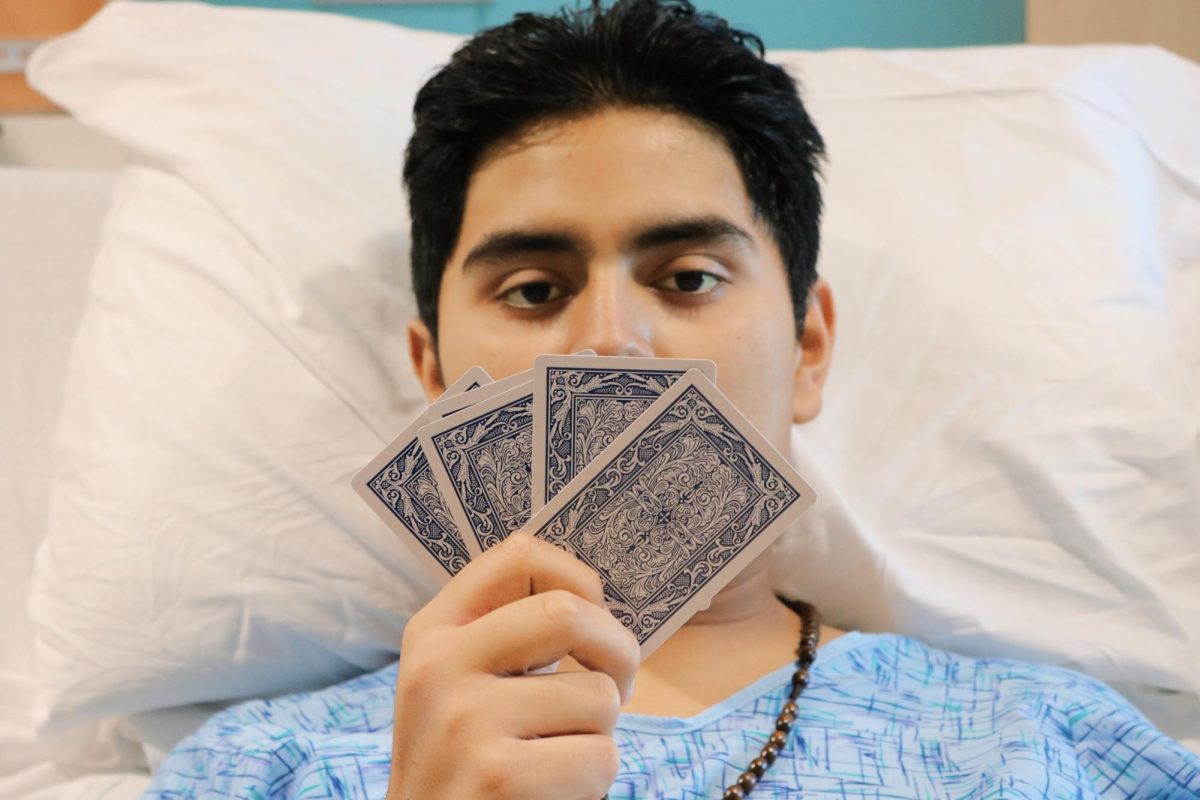 Joshua covers half of his face with a card spread. 